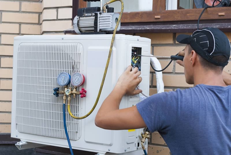 heating-contractor-working HVAC Technician working on a ductless heat pump