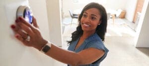 Woman adjusting the Heating Thermostat