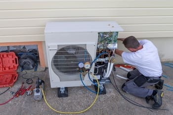 Heat-Pump-Repair-SeaTac-WA-98188 Technician repairing outdoor HVAC unit.