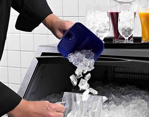 manitowoc-ice-machine-restaurants Restaurant staff using a plastic scoop to collect fresh cubes from a Manitowoc commercial ice machine.